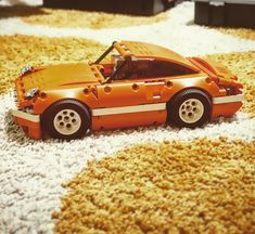 an orange toy car sitting on top of a carpet covered in white and yellow stuff