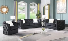 a living room filled with black couches and white pillows on top of a rug