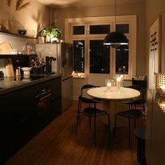 a table with candles on it in a kitchen next to an oven and window at night