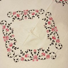 a white table cloth with pink flowers and black scrolls on it, in the shape of a square