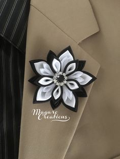 a man wearing a tan suit with a black and white flower brooch on his lapel