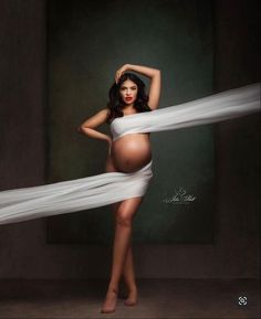 a pregnant woman in a white dress is posing for the camera with her hands on her hips