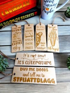 wooden bookmarks with words on them sitting next to books and a cup of coffee