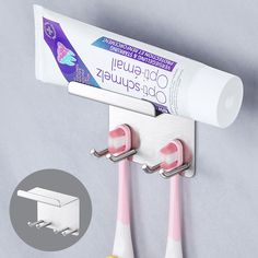 two toothbrushes are hanging on the wall next to some toothpaste tubes