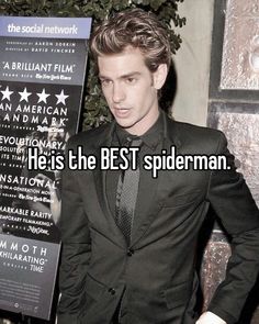 a man in a suit and tie standing next to a sign that says he's the best spiderman