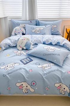 a bed with blue comforters and stuffed animals on the sheets in front of a window