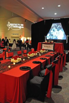 a long table is set up with black plates and red cloths for an event