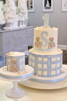 two tiered cake decorated with teddy bears and the number one on each side, sitting on a table