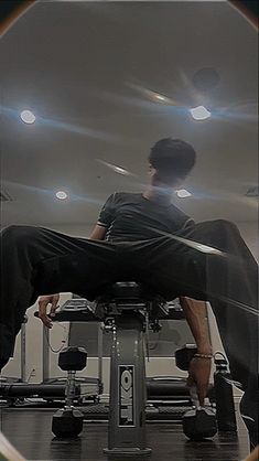 a man sitting on top of a machine in a gym