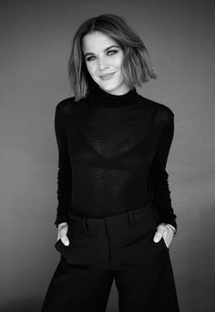 a black and white photo of a woman wearing a turtle neck top with wide legged pants