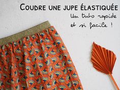 an orange and blue patterned skirt next to a red fan on a white wall with the words courre une jupe elastiquee