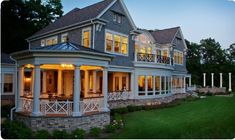 a large house lit up at night with lights on the front porch and covered patio