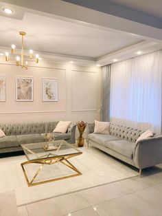 a living room filled with furniture and a chandelier hanging from the ceiling above it