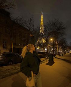 a woman standing in front of the eiffel tower at night with her hand on her hip