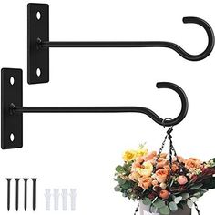 two black metal hooks with flowers hanging from them and screws on the wall next to it