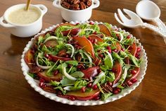 a salad in a bowl on a wooden table with spoons and bowls around it