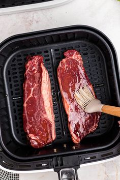 two raw meats are being cooked in an air fryer with a spatula