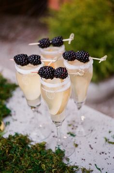 three glasses filled with champagne and blackberries