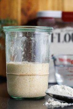 a glass jar filled with food sitting on top of a table next to a spoon