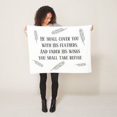 a woman holding up a sign that says he shall cover you with his feathers and under his wings you shall take refuge