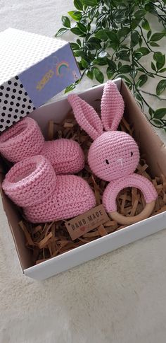 a pink knitted bunny in a box next to a plant