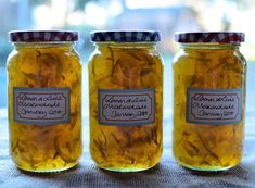 three jars filled with yellow flowers sitting on top of a table