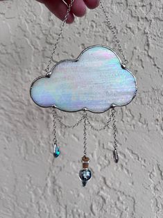 a hand holding a metal chain with a white cloud hanging from it's side