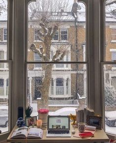 an open laptop computer sitting on top of a wooden desk in front of a window