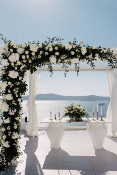 an outdoor ceremony setup with white flowers and greenery on the altar, overlooking the ocean