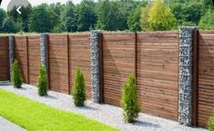 a wooden fence is lined with plants and rocks