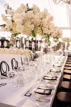 a long table is set with glasses and place settings for an elegant wedding reception in black and white