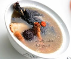 a white bowl filled with soup and meat on top of a table next to an orange slice