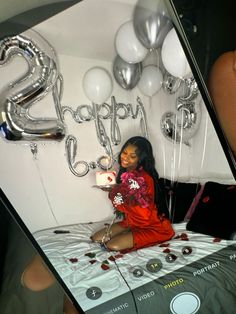 a woman sitting on top of a bed next to balloons