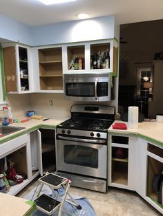 the kitchen is being remodeled with new appliances and cabinets painted green, white and gray