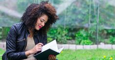 a woman sitting on the ground reading a book