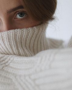 a close up of a person wearing a turtle neck sweater and looking at the camera