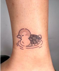 a small tattoo on the ankle of a woman's neck depicting a duck swimming in water