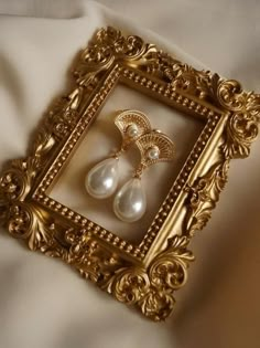 an ornate gold frame with two pearls in it