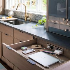 an open laptop computer sitting on top of a kitchen counter next to a sink and window