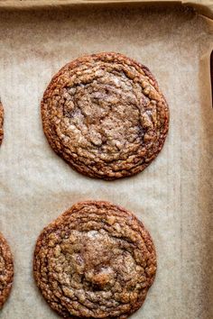 four cookies are sitting on top of a piece of parchment paper in a baking pan