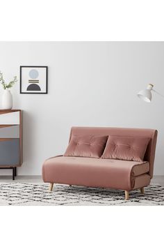 a living room with a pink couch and white rug in front of a wall mounted lamp