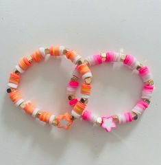 two bracelets with pink, orange and white beads on them sitting next to each other