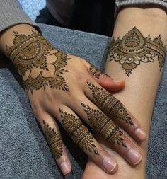 two women with henna tattoos on their arms and hands, both holding each other