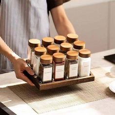 a person holding a tray with spices on it in front of a plate full of sauces