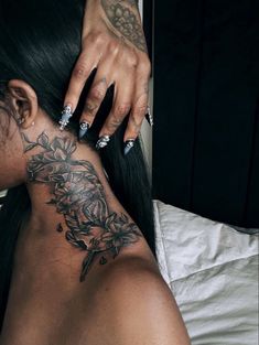 a woman with tattoos on her neck is laying down and touching the back of her head