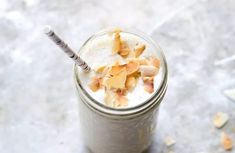 a glass filled with milk and topped with chopped up pieces of fruit on the side