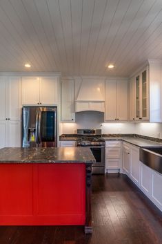 a kitchen with white cabinets and red island