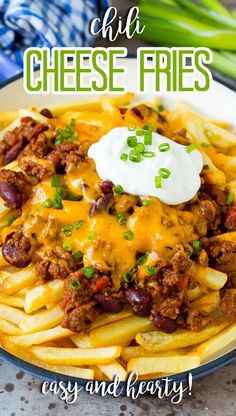 chili cheese fries on a plate with sour cream in the middle and green onions to the side