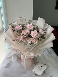 a bouquet of pink roses sitting on top of a white table next to a card