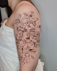 a woman's face with flowers and leaves on her arm, in black and white